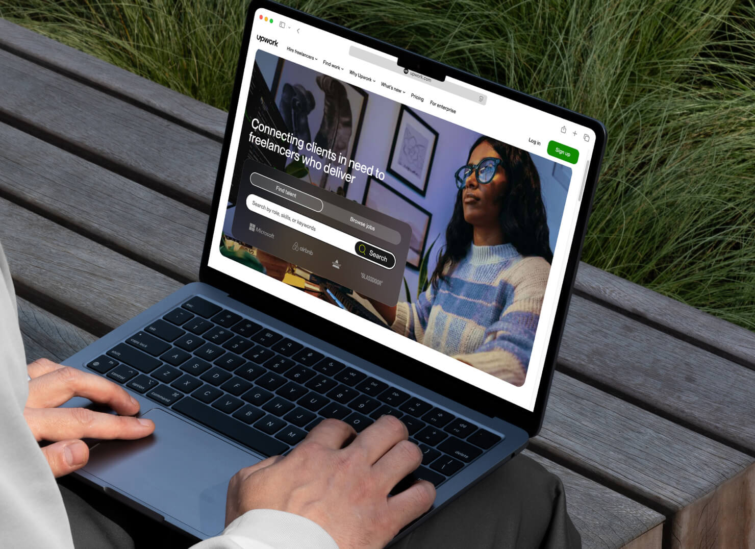 Designer’s hands on a MacBook with the main page of Upwork.